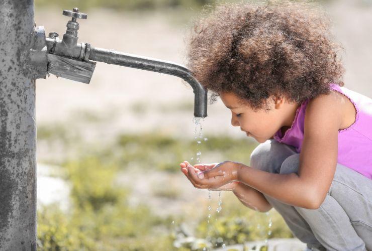 bambina beve l'acqua corrente