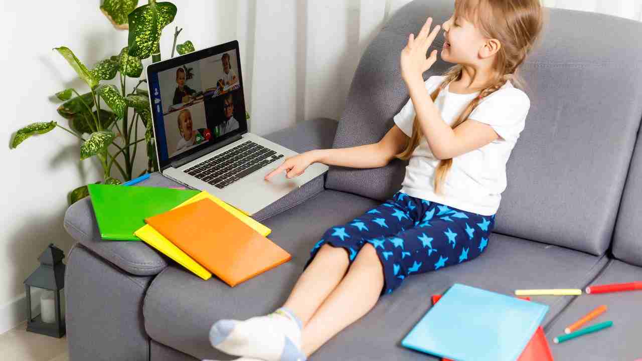 bambina sul divano con libri e colori